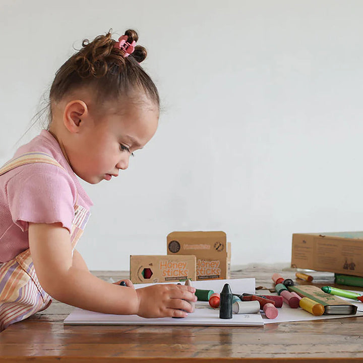 Child drawing at a table with art supplies